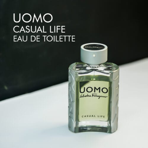 A 100ml bottle of Salvatore Ferragamo Uomo Casual Life Eau de Toilette with a sleek, transparent glass design, a silver collar, and a grey cap, placed on a white table.