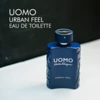 A 100ml bottle of Salvatore Ferragamo Uomo Urban Feel Eau de Toilette with a modern, blue glass design, placed on a white table.