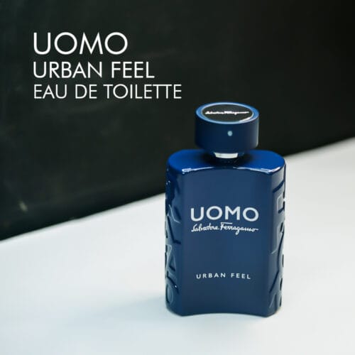 A 100ml bottle of Salvatore Ferragamo Uomo Urban Feel Eau de Toilette with a modern, blue glass design, placed on a white table.