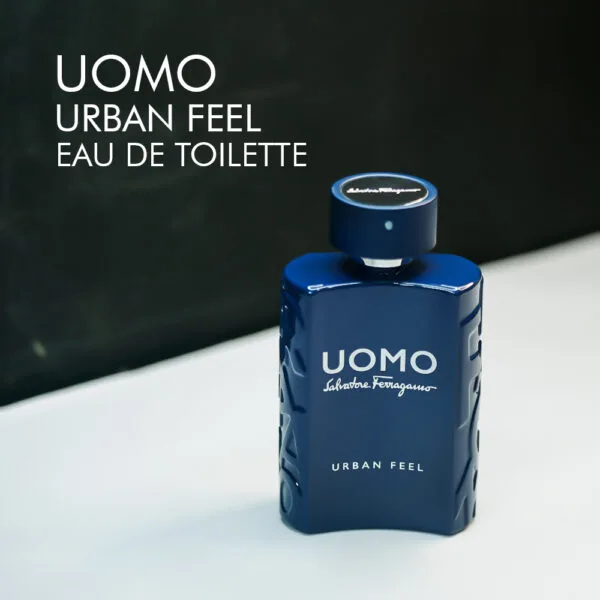A 100ml bottle of Salvatore Ferragamo Uomo Urban Feel Eau de Toilette with a modern, blue glass design, placed on a white table.
