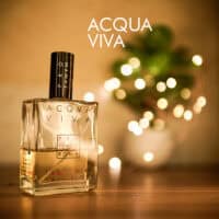 A 100ml bottle of Profumum Roma Acqua Viva Parfum with a square amber glass design and black cap, placed on a brown table.