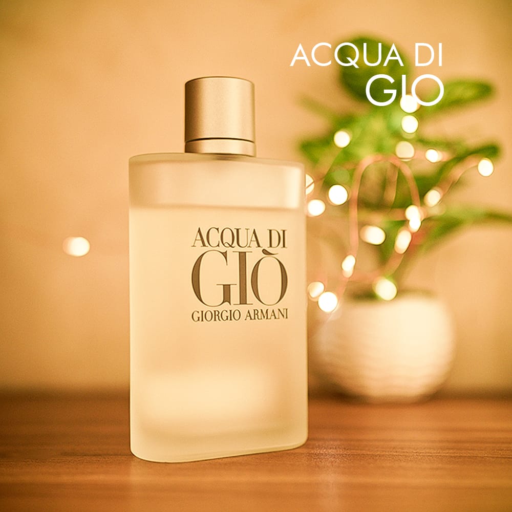 A 100ml bottle of Giorgio Armani Acqua Di Gio Eau de Toilette with a clear glass bottle and silver-toned cap, displayed on a brown table.