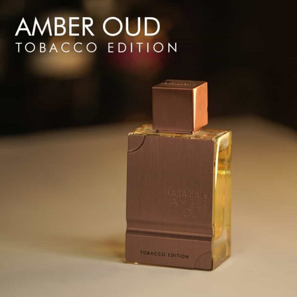 A 100ml bottle of Al Haramain Amber Oud Tobacco Edition Eau de Parfum with a rectangular glass body, gold label, and gold cap on a brown table.