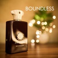 boundless A 100ml bottle of Amouage Boundless Eau de Parfum with a translucent amber glass and a pink-white cap on a brown table.
