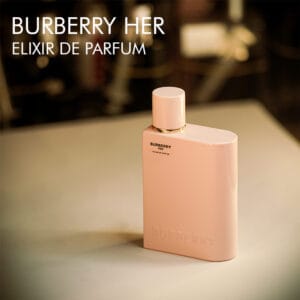 A 100 bottle of Burberry Her Elixir Eau de Parfum with a pink design on a brown table.