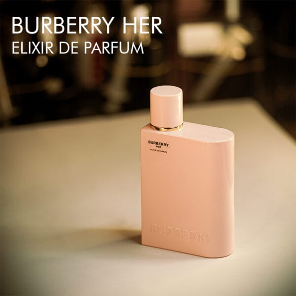 A 100 bottle of Burberry Her Elixir Eau de Parfum with a pink design on a brown table.