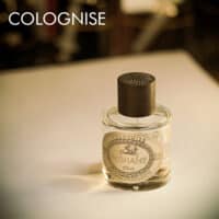 a 100ml bottle of Nishane Hesperide Colognise Extrait de Cologne with a cylindrical glass design, light yellow liquid, and a brown cap on a brown table.