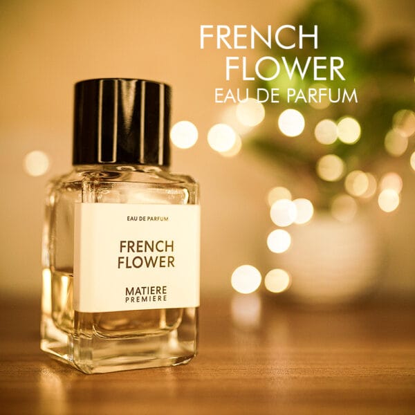 a 100ml bottle of Matiere Premiere French Flower Eau de Parfum with a sleek, cylindrical clear glass design and a black cap on a brown table.