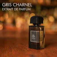 A 100ml bottle of BDK Parfums Gris Charnel Extrait de Parfum, with a dark glass bottle, set on a brown table.