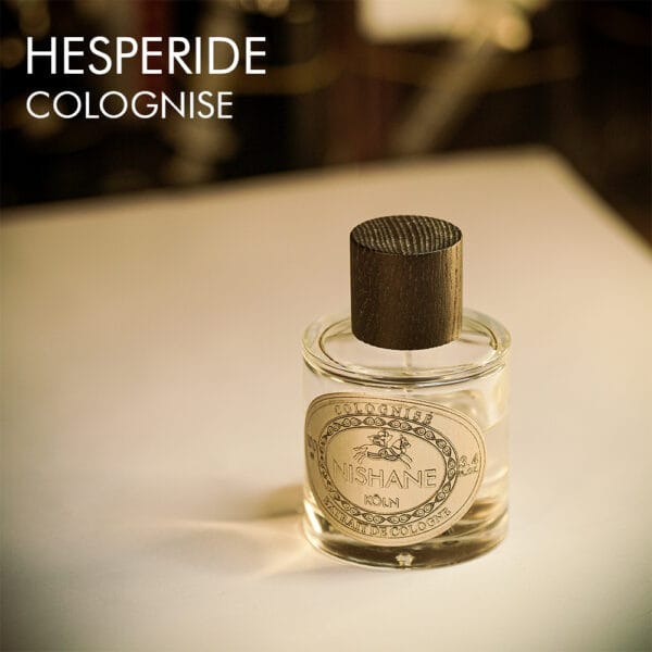 a 100ml bottle of Nishane Hesperide Colognise Extrait de Cologne with a cylindrical glass design, light yellow liquid, and a brown cap on a brown table.