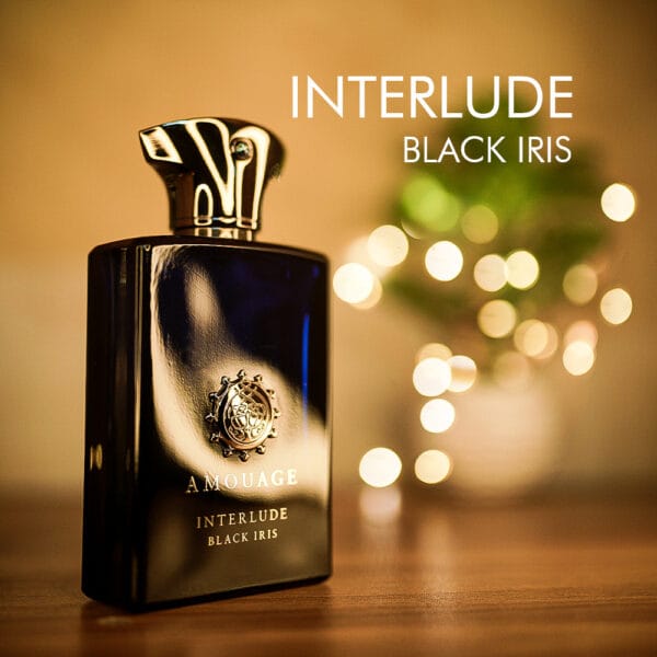 A 100ml bottle of Amouage Interlude Black Iris Eau de Parfum with dark blue glass and a silver cap on a brown table.