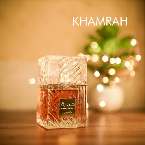 A 100ml bottle of Lattafa Khamrah Eau de Parfum, designed in a square shape with intricate golden patterns and a clear cap, placed on a brown table.