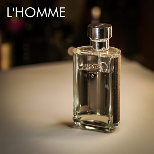 A 100ml bottle of Prada L’Homme Eau de Toilette with a clear glass design and silver cap, placed on a white table.