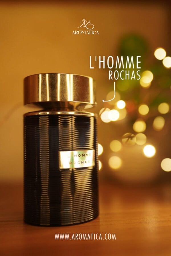 A 100ml bottle of Rochas L’Homme Eau de Toilette with a cylindrical blue glass design and silver cap, placed on a brown table.