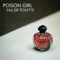 A clear bottle with red tinted liquid of Dior Poison Girl Eau De Toilette with black font labels.
