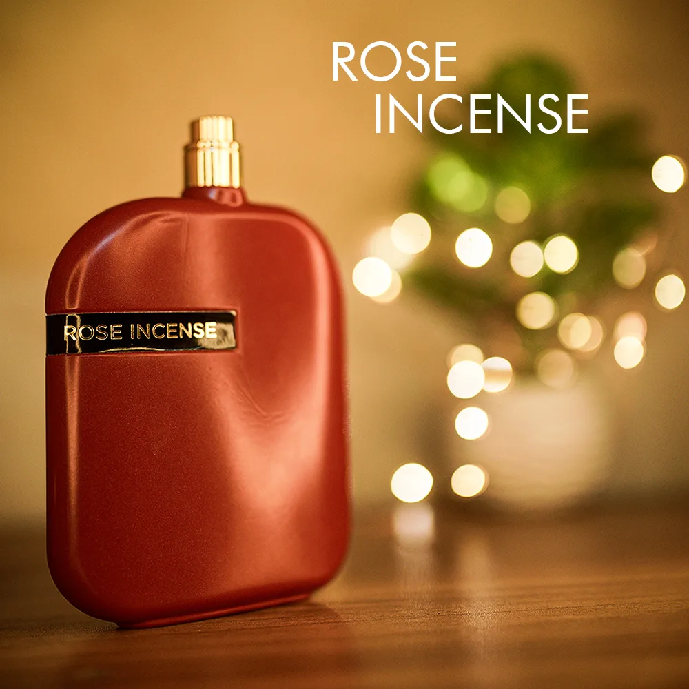 A 100ml bottle of Amouage Rose Incense Eau de Parfum with metallic red and a gold round cap on a brown table.