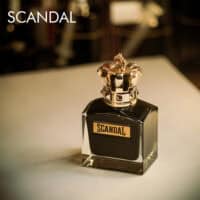 A 100ml bottle of Jean Paul Gaultier Scandal Le Parfum Eau de Parfum Intense, black glass bottle, gold cap on a brown table.