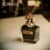 A 100ml bottle of Jean Paul Gaultier Scandal Le Parfum Eau de Parfum Intense, black glass bottle, gold cap on a brown table.