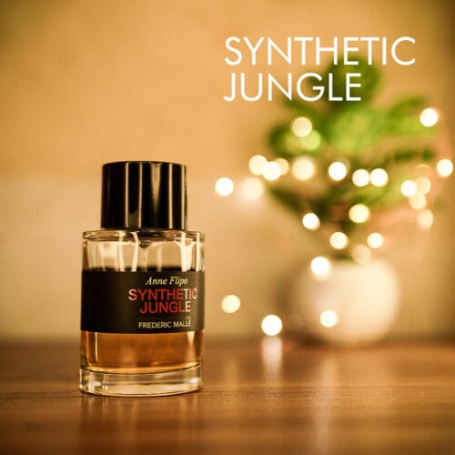 A 100ml bottle of Frederic Malle Synthetic Jungle Eau de Parfum with a cylindrical glass bottle, clear with a black label, and a black cap, placed on a brown table.