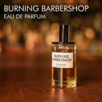 a 100ml bottle of D.S. & Durga Burning Barbershop Eau de Parfum with a minimalist cylinder glass design and black cap on a brown table.