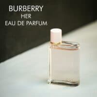 A clear bottle with light pink liquid of Burberry Her Eau De Parfum with engraved labels.
