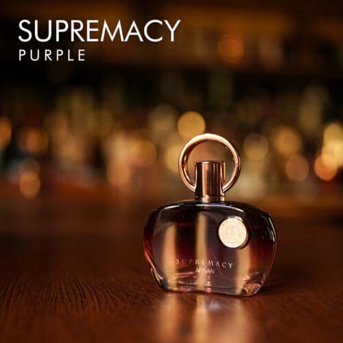 a 100ml bottle of Afnan Supremacy Purple Eau de Parfum with a purple metallic glass design and gold cap on a brown table.