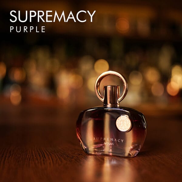 a 100ml bottle of Afnan Supremacy Purple Eau de Parfum with a purple metallic glass design and gold cap on a brown table.