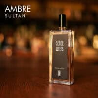a 100ml bottle of Serge Lutens Ambre Sultan Eau de Parfum with a rectangular glass design and black cap on a brown table