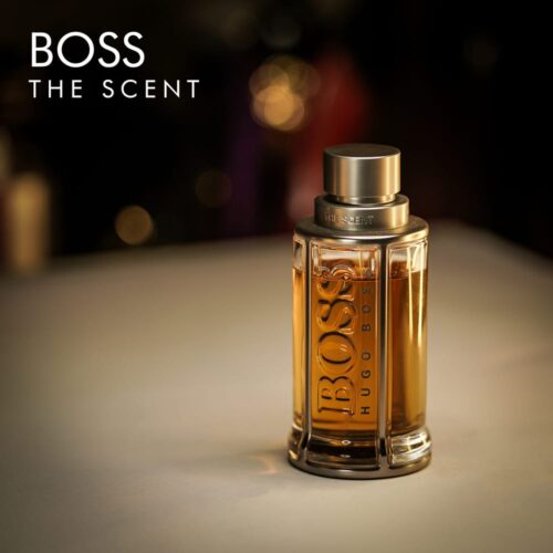 a 100ml bottle of Hugo Boss Boss The Scent Eau de Toilette with an amber-tinted glass design and silver cap on a white table