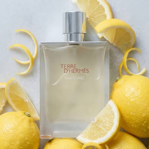 31 Fresh lemon-scented Terre d'Hermès Eau Givrée perfume surrounded by whole and sliced lemons, emphasizing vibrant citrus notes.