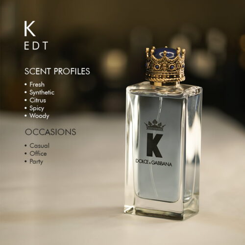 A 100ml bottle of Dolce & Gabbana K Eau de Toilette with a crown-shaped cap and light blue liquid, placed on a white table.