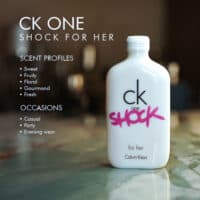 A 100ml bottle of Calvin Klein CK One Shock For Her Eau de Toilette with a white design and pink label on a marble table.