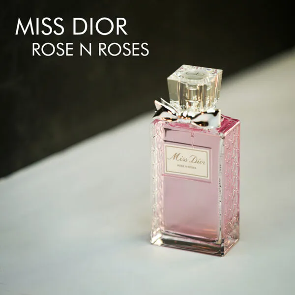 A clear bottle with light pink liquid and a silver ribbon of Miss Dior Rose N' Roses Eau De Parfum with gold font labels.