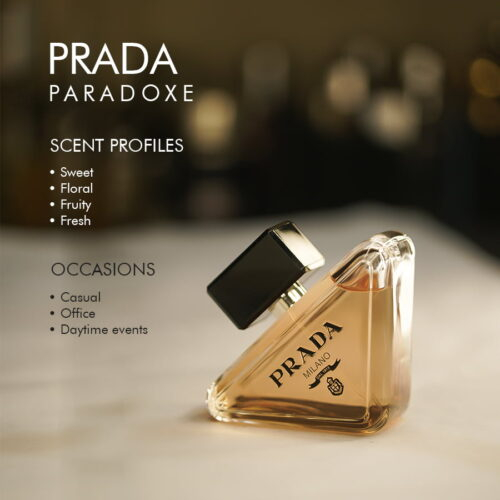 A 100ml bottle of Prada Paradoxe Eau de Parfum with a black cap and coral-pink liquid featuring the Prada coat of arms on a marble table.