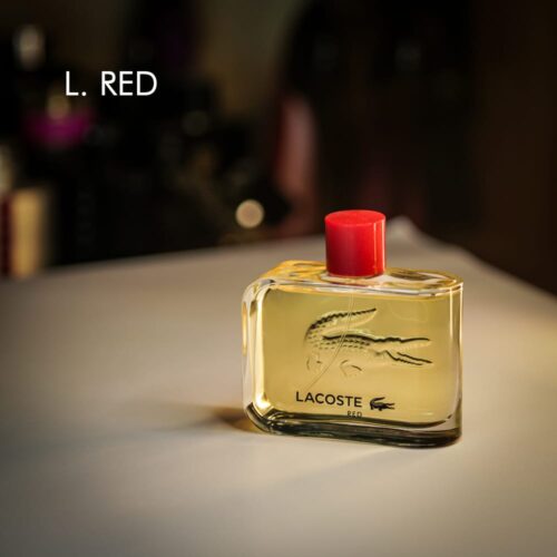 A 100ml bottle of Lacoste Lacoste Red Eau de Toilette with a red cap and clear yellow liquid on a white table