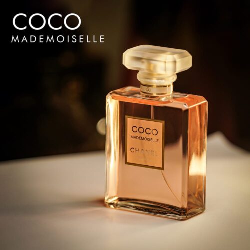 A 100ml bottle of Chanel Coco Mademoiselle Eau de Parfum with a clear design and a clear cap and pinkinsh liquid on a white table