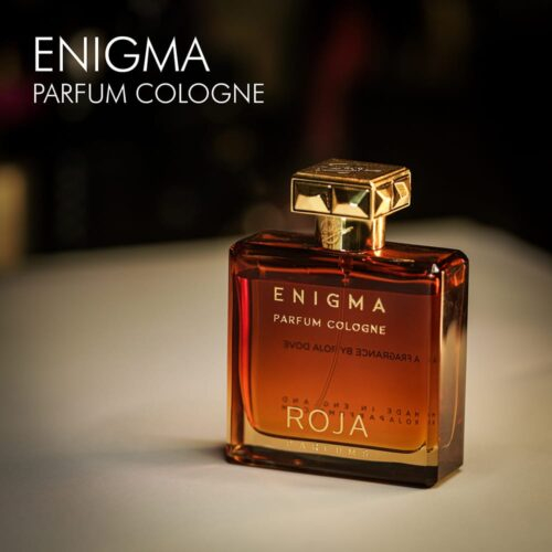 A 100ml bottle of Roja Parfums Enigma Pour Homme Parfum Cologne with a brown bottle design and a gold cap on a white table