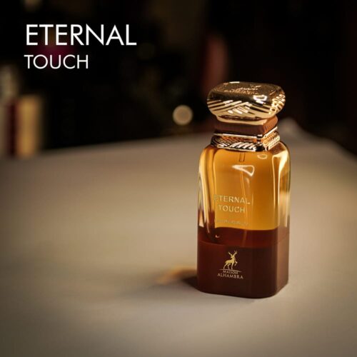 A 100ml bottle of Maison Alhambra Eternal Touch Eau de Parfum with a gold and deep red design on a white table