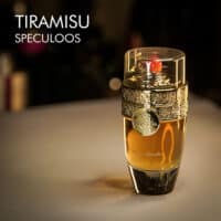 A 100ml bottle of Paris Corner Tiramisu Speculoos Eau de Parfum with a brown and gold design on a white table