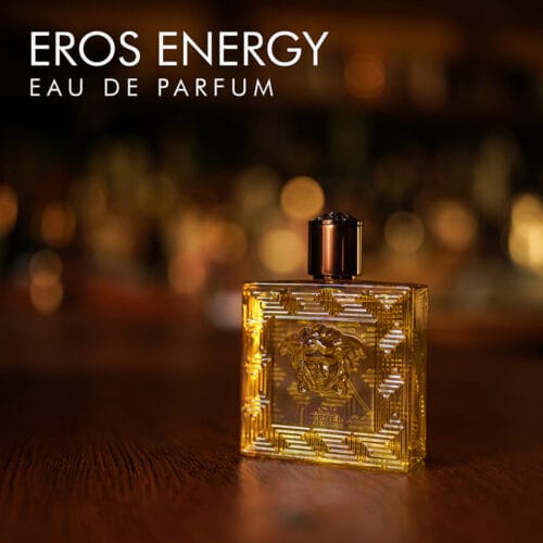 A 100ml bottle of Versace Eros Energy Eau de Parfum with a yellowish design and clear liquid with a golden label on a brown table