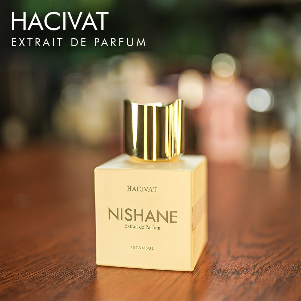 A 100ml bottle of Nishane Hacivat Extrait de Parfum with a sleek white and gold design on a white table