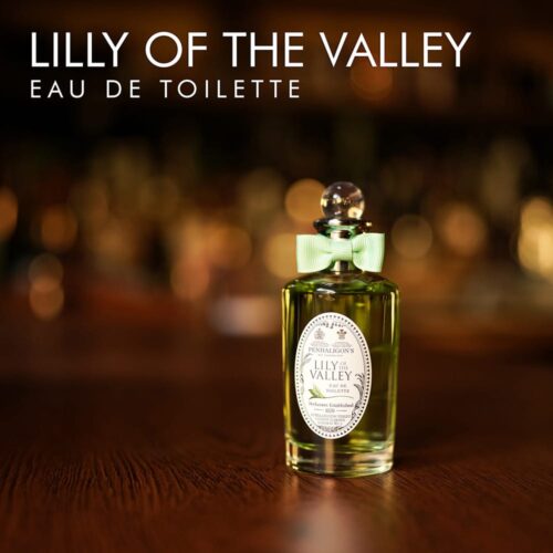 A 100ml bottle of Penhaligon's Lily of the Valley Eau de Parfum with a clear cap and greenish liquid with a white label on a brown table