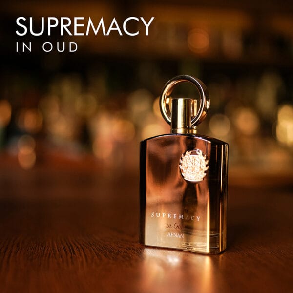 A 100ml bottle of Afnan Supremacy In Oud Eau de Parfum with a luxurious rugged gold design on a white table