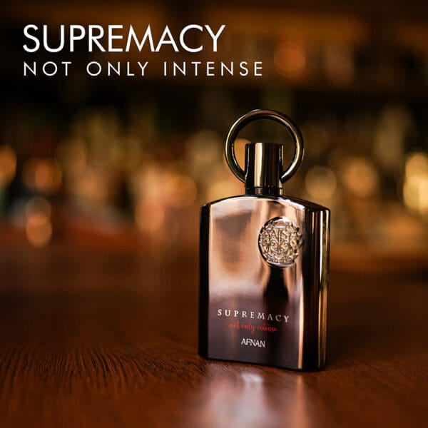 A 100ml bottle of Afnan Supremacy Not Only Intense Extrait de Parfum with a brown and silver design and a round shape on a brown table