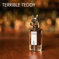 A 100ml bottle of Penhaligon's Terrible Teddy Eau de Parfum with a clear cap and murky liquid with a white label on a brown table