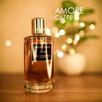 amore caffe A 120ml bottle of Mancera Amore Caffè Eau de Parfum with a brown tinted glass body, a gold cap, a black label on a brown table.