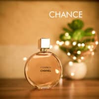 A 100ml bottle of Chanel Chance Eau de Toilette with a transparent cap, black label, yellowish liquid on a brown table