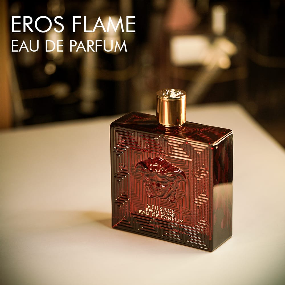 A 100ml bottle of Versace Eros Flame Eau de Parfum with a bold red design and golden label on a white table