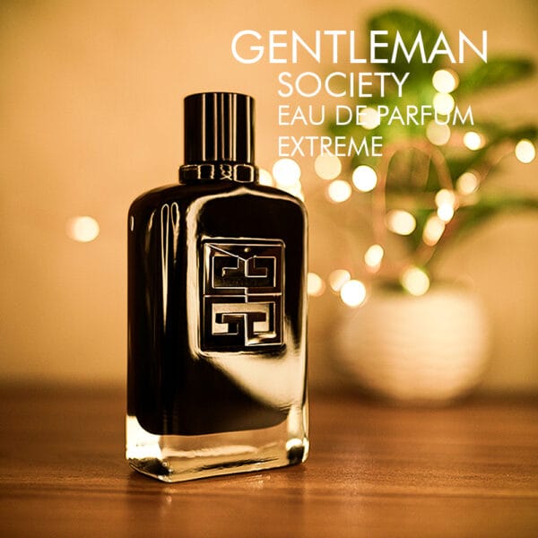 A 100ml bottle of Givenchy Gentleman Society Eau de Parfum Extreme with a black design and black cap on a brown table.