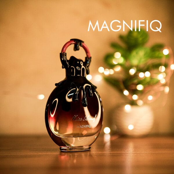 A 100ml bottle of Miss Armaf Magnifiq Eau De Parfum with a purple-black design and black orante cap on a brown table.